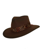 Three-quarter angled view of a dark brown wide-brim fedora with an teardrop crown crease and layered rust-tone feather hat band.
