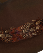 Close-up view of a dark brown wide-brim fedora and layered rust-tone feather hat band.
