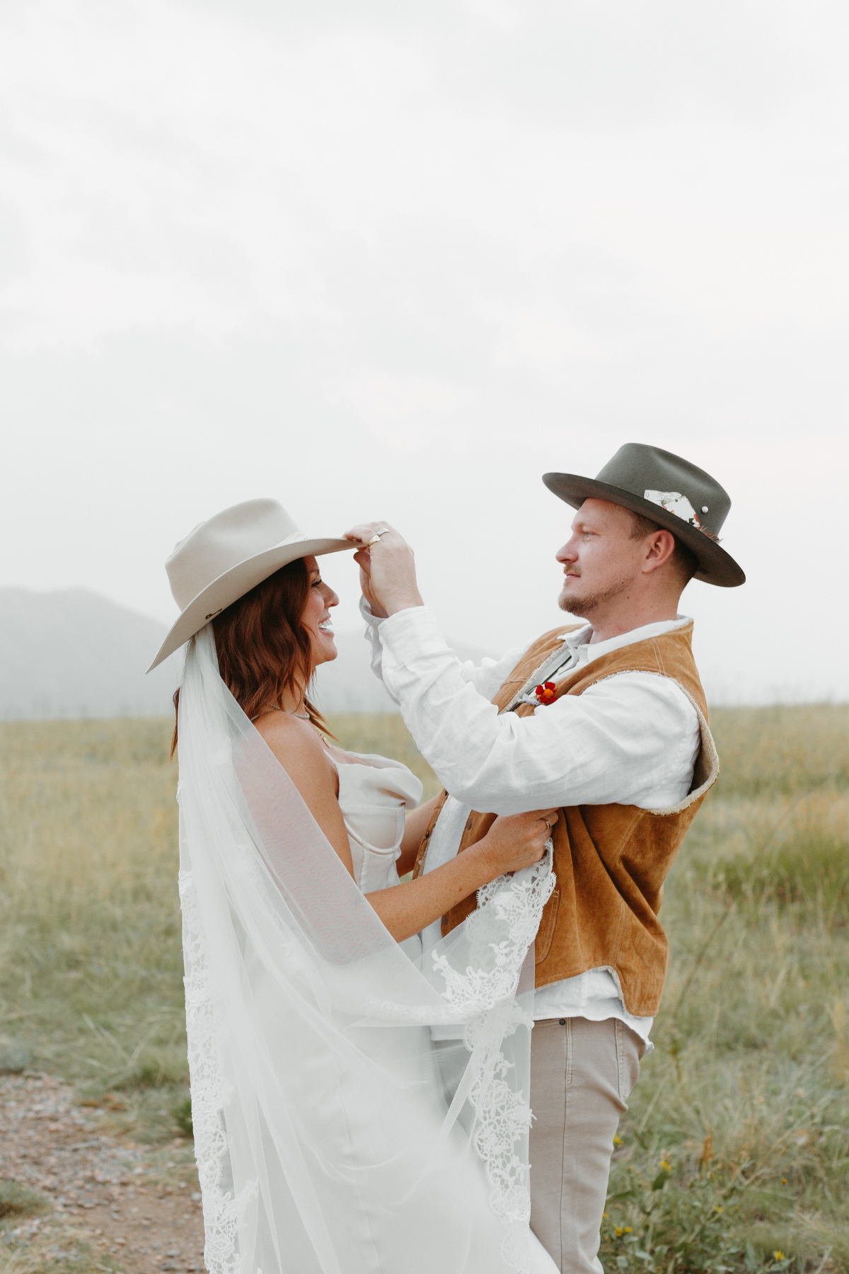 Parker and Janelle wedding photo of them in custom cowboy hats take in an open space in colorado 