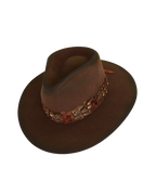Three-quarter angled top view of a dark brown wide-brim fedora with an teardrop crown crease and layered rust-tone feather hat band.
