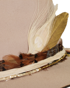 Close-up view of a light tan wide-brim felt fedora with a hand-burned crown edge and layered feather hat band with quartz stones.